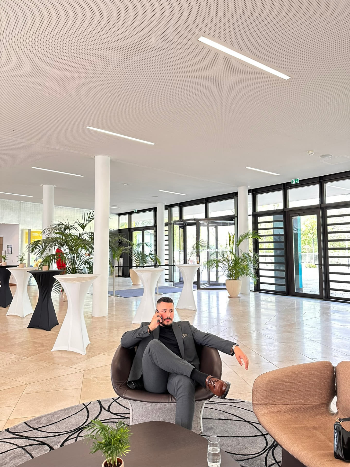 Farshad Sahab im Anzug in einer hellen Bürolobby während eines Telefonats